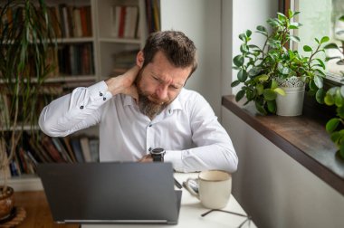 İş adamı dizüstü bilgisayarda çalışıyor ve ofis sendromu yaşıyor.