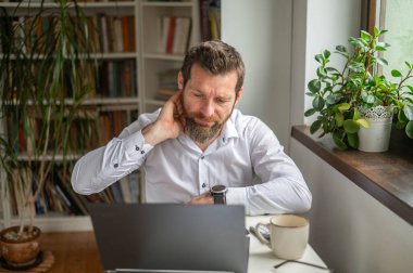 İş adamı dizüstü bilgisayarda çalışıyor ve ofis sendromu yaşıyor.