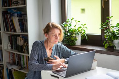 Konforlu bir ofiste doğal ışıkla çalışan odaklanmış bir kadın. Konforlu Uzak Çalışma