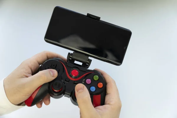 Game Pad with smartphone in hands on white background. Mobile Gaming concept. a blank white screen on a smartphone. copy space.