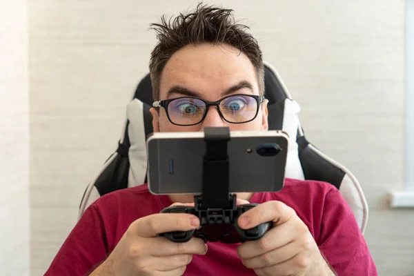 スマートフォンに接続されたゲームコントローラーを持つ男の手 電子機器と技術の概念 — ストック写真