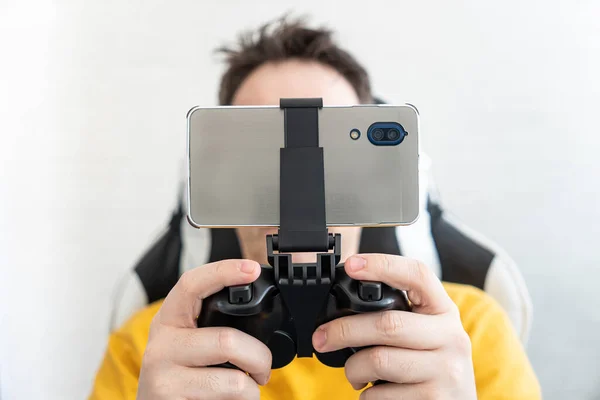 スマートフォンで遊んでいる男 スマートフォンにワイヤレスで接続されたジョイスティック ゲームは電話中だ — ストック写真