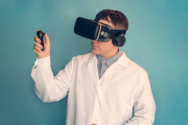 Medical doctor using virtual reality headset at his work. a doctor in a VR helmet on a blue background. telemedicine concept