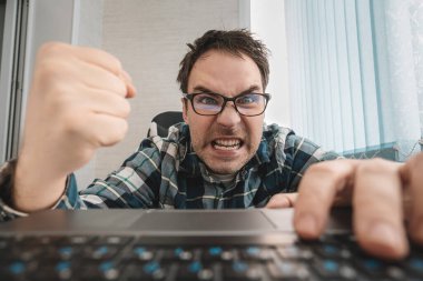 Sinirli bir adam bilgi teknolojisine küfrediyor ve küfrediyor ve onun kompüter endişeleri ve sıkıntıları - bilgisayarlardan nefret etme kavramı. Ofisteki gömlekli iş adamı klavyeyi yumrukluyor..