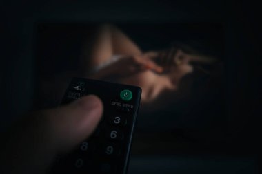 Porno TV - Pornografi. Erotik bir filmin arka planında odaklı olmayan bir adamın uzaktan kumandası. Oteldeki kablolu kanalda yetişkin içeriği