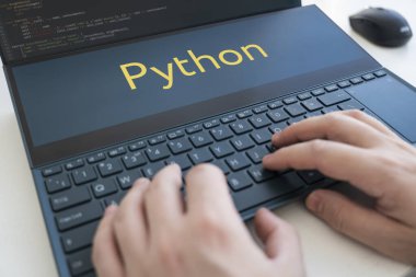 Bir programcı Python 'da bir program yazar. Siyah klavyede erkek elleri