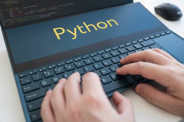 Bir programcı Python 'da bir program yazar. Siyah klavyede erkek elleri