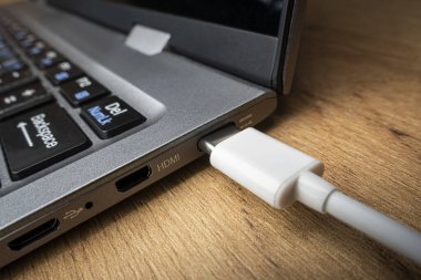C tipi konnektör altındaki kablo USB adaptörü, tahta bir masanın arka planına karşı dizüstü bilgisayarda kurulur