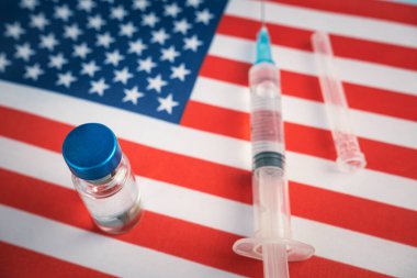 Amerikan bayrağının ayağına şırınga ve aşı. ABD 'de sağlık hizmeti kavramı