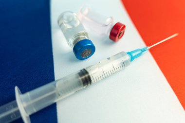 Eczacılık ve Tıp Fransa konsepti. Coronavirus covid aşısı. Aşı ampulleri, ulusal bayrağın arka planına karşı şırınga. Ulusal farmakoloji endüstrisi.