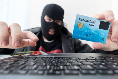 Soyguncu maskeli adam internet, banka hesabı ve kredi imkanları kullanır. Kimlik avı saldırısı gizli yüzü olan bir erkek. Hacker çalıntı mali veri girer. Gizli bilgiler dolandırıcı tarafından alınmıştır.