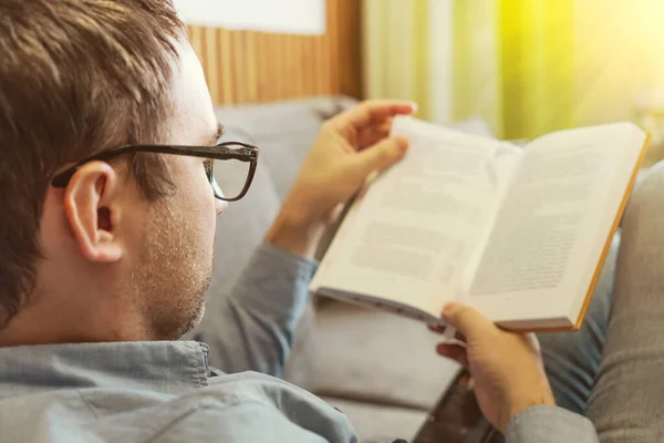 文学和人的观念 一个人坐在沙发上 在家看书 读者正在阅读一本小说 一个学生正在学习一本书 这家伙手里拿着一本书 — 图库照片