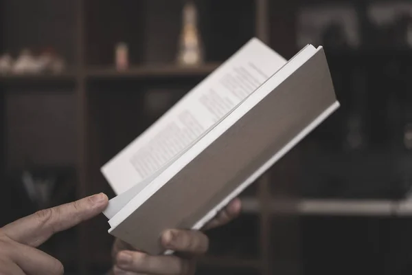 男性の手は暗い背景の白い表紙に本を開いています — ストック写真
