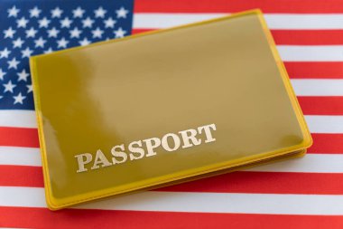 Pasaportlu Amerikan bayrağı. Seyahat vizesi ve vatandaşlık konsepti. Ülkede oturma izni. Bayrağın üzerinde yazılı pasaportu olan sarı bir belge var. Kapat, üst görünüm