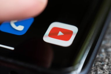 Bir akıllı telefon karanlıkta bir masanın üzerinde, YouTube 'un logosunu sergiliyor. Dokunmatik ekranın üstündeki parmak. Barnaul. Rusya 20 Haziran 2022