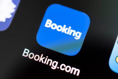 Barnaul. Rusya 20 Haziran 2022: bir otel odasındaki bir yatağın arka planındaki Booing.com uygulamasında el sıkışması. Online rezervasyon.