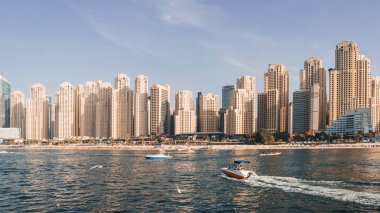 Dubai Marina Panorama 'sı bir yaz günü, BAE. Sürat teknesi turistleri Dubai kıyısı yakınlarındaki körfezdeki suya götürüyor.