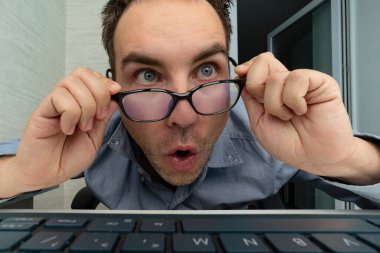 Genç adam dizüstü bilgisayarıyla şaşırdı. Ofisteki bir çalışan şaşkınlıkla ekrana bakıyor. Çılgın programcı iş başında. Aptal inek bir video izliyor..