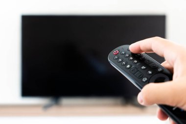 Uzaktan adamla el spor kanalı izlediğini kontrol ve Uzaktan kumanda üzerindeki düğmeye basmadan. Uzaktan kumanda el closeup içinde.