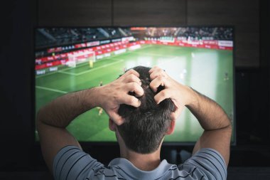 Goal. Man watching football match on television at home. emotional fan watching football at night, view from the back clipart