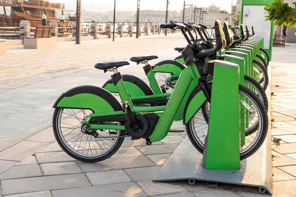 stock image electric bicycles for rent are green in the parking lot in the city center on the street. Eco-friendly mode of transport