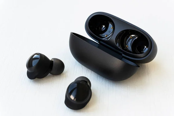 Wireless black earphones with contactless charging close-up on a white background. box with wireless headphones.