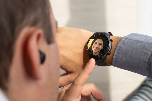 attractive man looking on watch while talking by smartphone. incoming call on a modern smart watch. the guy presses a button on his watch.