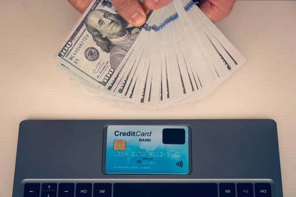 人は現金概念の代りにクレジットカードを使用してインターネットを通してオンラインで買物をするドル札を持っている 投資収益 オンライン ワーク マネージャーの給与 — ストック写真