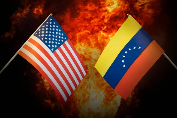 激しい爆発を背景に ベネズエラとアメリカの旗 国家間の敵意と戦争の概念 政治的緊張関係 — ストック写真