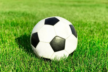 Klasik futbol topu, tipik siyah-beyaz desenli, stadyumun sahasında. Geleneksel futbol topu yeşil çimenlik alanda.