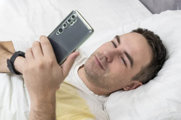 Hombre Alegre Despertó Mañana Dormitorio Utiliza Teléfono Inteligente Vista Superior — Foto de Stock