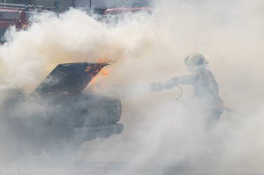 Yangın söndürücü yanan bir arabayı yangın hortumu, yangın ve otomatikten söndürür. Bir itfaiyeci yangın söndürücüyle bir arabayı söndürüyor..