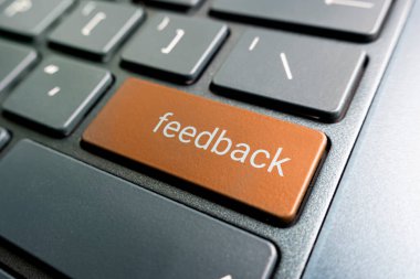 press orange feedback button on laptop keyboard. feedback inscriptions on the keyboard button close up clipart