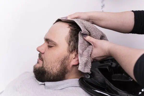Κομμωτής Πλύνει Μαλλιά Του Πελάτη Στο Κουρείο Ένας Νεαρός Γενειοφόρος — Φωτογραφία Αρχείου