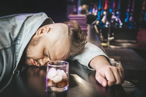 Alkoholismus Sklíčený Mladý Muž Spí Stole Zatímco Pije Alkoholický Nápoj — Stock fotografie