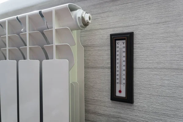 Heating radiator thermostat set to low temperature and room thermometer for saving money at heating costs. Energy crisis, energy efficiency and rising heating costs in Europe
