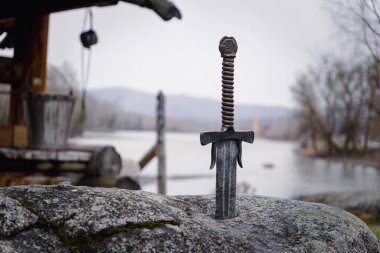 famous sword excalibur of King Arthur stuck in the rock. Edged weapons from the legend Pro king Arthur. clipart
