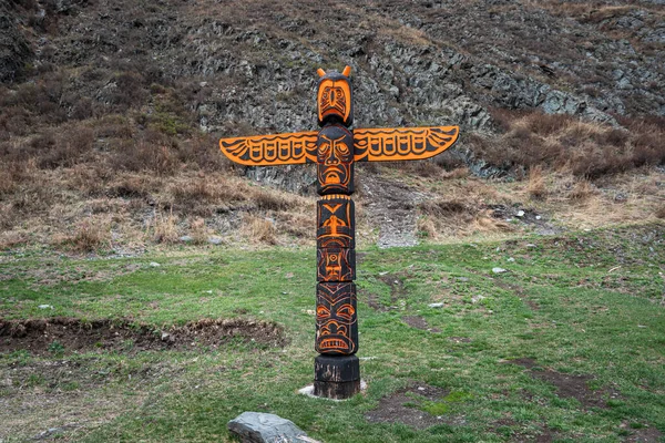 Totem pole with eagle and wings against the background of nature