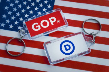 ABD bayrağının arka planında ABD partilerinin logolarının olduğu anahtarlıklar. Cumhuriyetçilerin ve Demokratların muhalifleri. Amerika Birleşik Devletleri 'nde seçimler. 24 Ağustos 2022