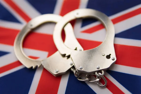 great britain flag and police handcuffs. The concept of crime and offenses in the country. the concept of crime in the state or government of the country.