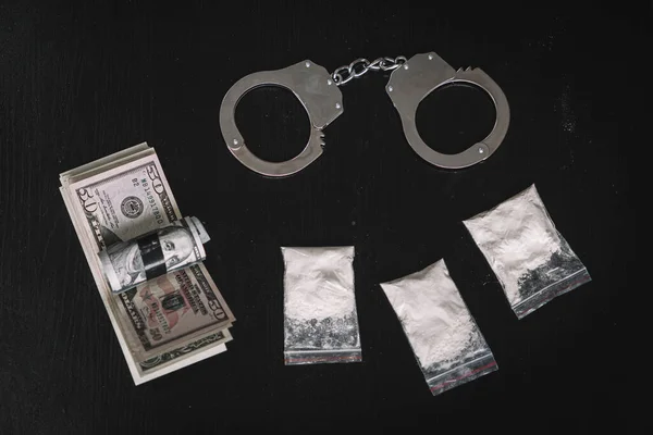 テーブルの黒の背景にお金と手錠の袋に麻薬の粉末 麻薬取引又は麻薬取引の概念 — ストック写真