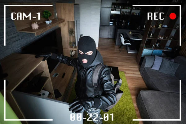 A man in a black mask is trying to rob a house. simulation of recording from a surveillance video camera. Robbery of a private house. Criminal concept, apartment theft