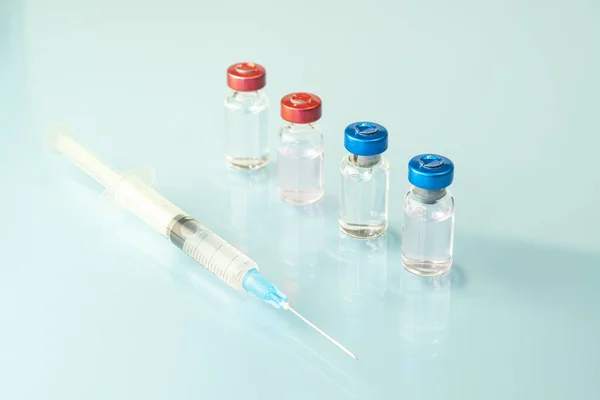 stock image One glass vial of liquid, a vaccine, and a medical syringe close-up on a blue background. The concept of vaccination against coronavirus. Banner, copy space.