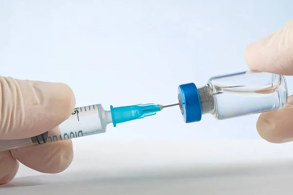 stock image Vaccine in vial with punctured syringe on a blue background