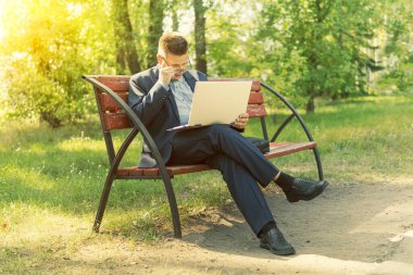 Serbest programcı dışarıda, parkta bir bankta dizüstü bilgisayar başında oturuyor. İş adamı laptopuyla kırsal bölgedeki kablosuz internete bağlanıyor. Aydınlık bir günde yaz parkında dizüstü bilgisayarlı bir adam