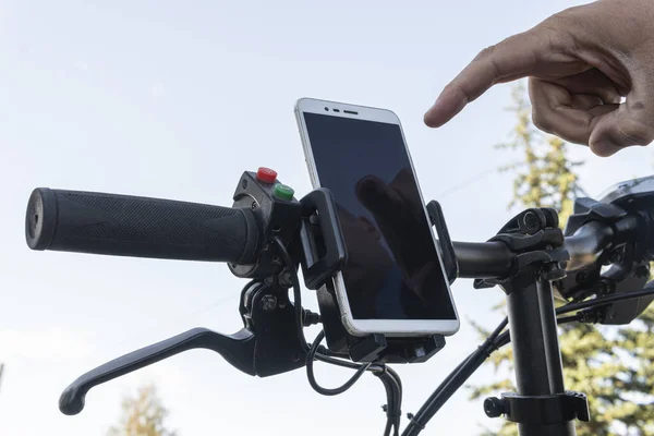cyclist hands use gps navigator on smartphone while biking. man presses his finger on the smartphone screen.