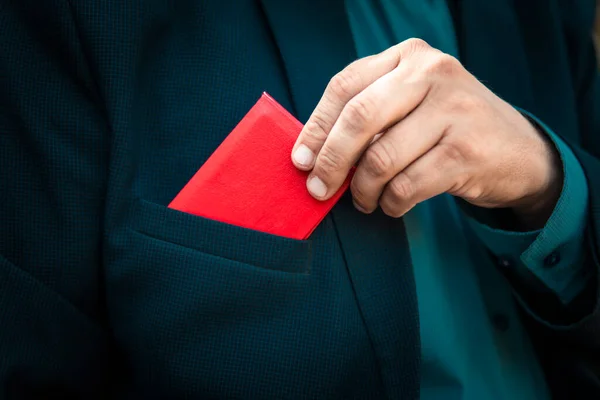 红色的身份证 有身份证的男人身穿蓝色西装的商人出示红色身份证或通行证 一个穿蓝色西装的男人从他的夹克口袋里掏出一张红色的身份证 — 图库照片
