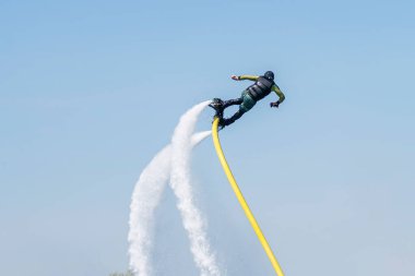 Bir adam Flyboard 'un üzerinde gökyüzünün arka planına karşı uçuyor. Sıra dışı spor