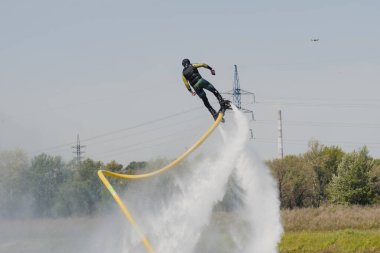 Bir adam Flyboard 'un üzerinde gökyüzünün arka planına karşı uçuyor. Sıra dışı spor