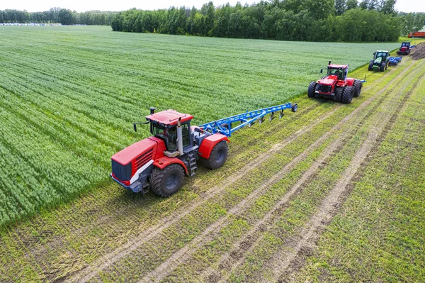Tractors with plow on soil cultivating. tractor bowling field, drone view. Cultivated plant and soil tillage. Agricultural tractors on field cultivation. Tractor disk harrow on plowing farm field.